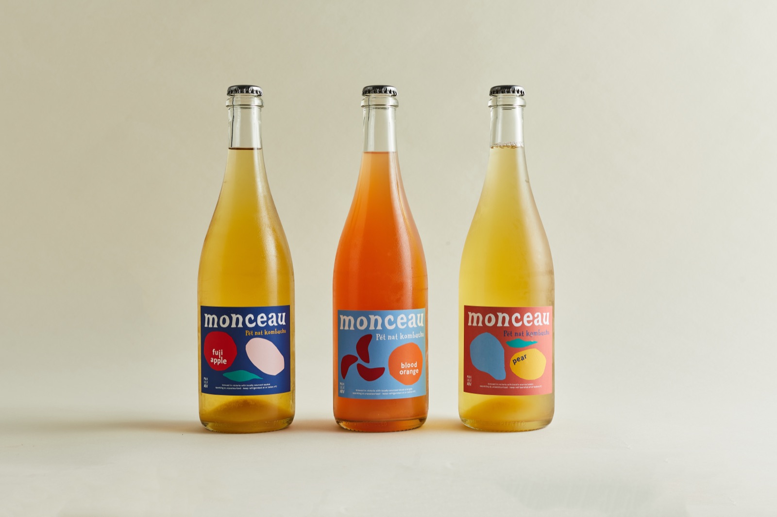 Three Monceau bottles, apple, blood orange and pear, in a studio